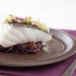 Dos de cabillaud cuit dans un lait parfumé à la citronnelle, accompagné de galettes de pommes de terre violettes croustillantes et d'une sauce fraîcheur au citron vert relevée au gingembre.